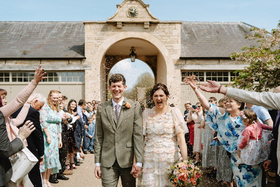 A picture of a bride and groom walking down an isle of their guests getting confetti thrown over them whilst celebrating